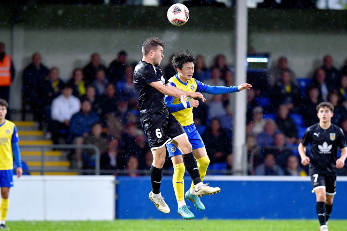 Two players competing for a header in the rain